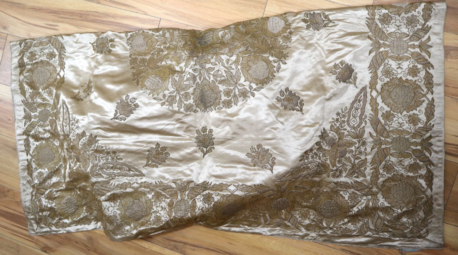 A silk bed cover, heavily embroidered in gold and silver coloured threads, silk lined in pale blue silk, 126 x 120cm
